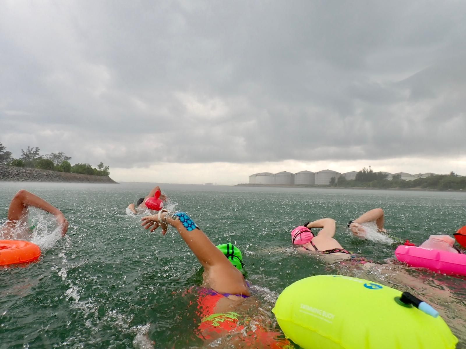Swimmers with tow floats swimming in open water off Singapore
